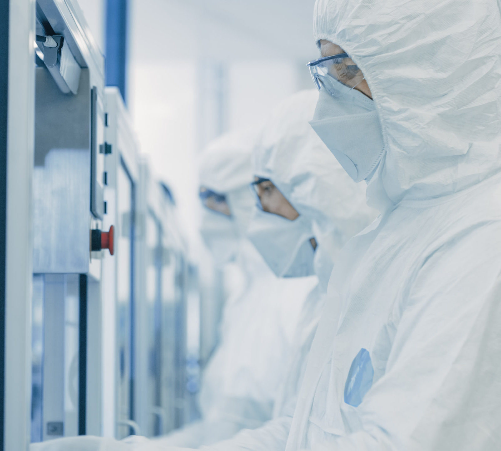 Semiconductor scientists wearing protective gear working on machines in factory